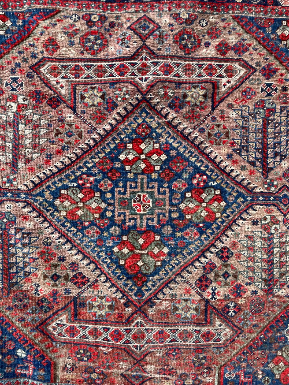 An antique hand-knotted wool carpet displaying a central diamond medallion, geometric borders, and an indigo field filled with intricate tribal motifs. View VIII