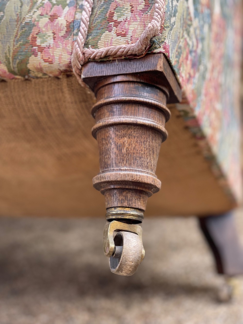 A two-seater Victorian style drop arm sofa upholstered in floral tapestry fabric with turned timber legs on brass castors. View VI