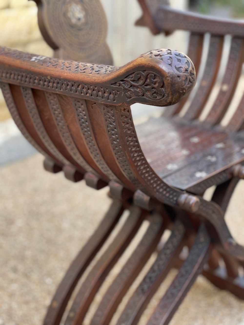 A dark carved wood X-frame armchair featuring intricate Arabic geometric fretwork and inlaid star motifs crafted from iridescent mother of pearl. View II