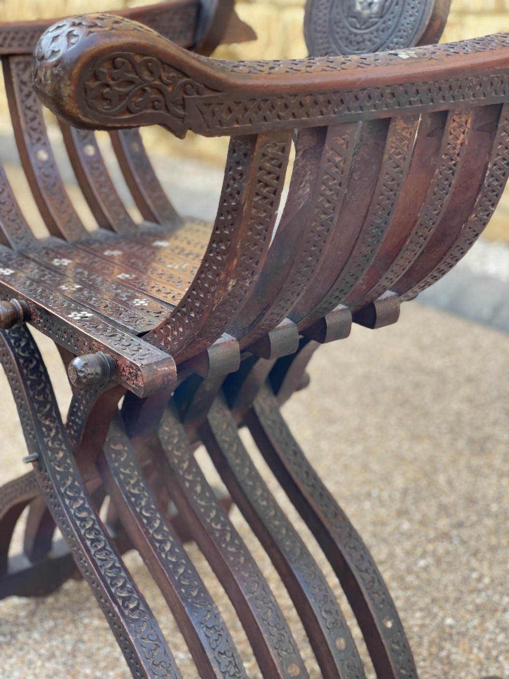A dark carved wood X-frame armchair featuring intricate Arabic geometric fretwork and inlaid star motifs crafted from iridescent mother of pearl. View III