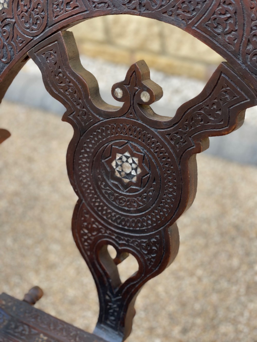 A dark carved wood X-frame armchair featuring intricate Arabic geometric fretwork and inlaid star motifs crafted from iridescent mother of pearl. View IV