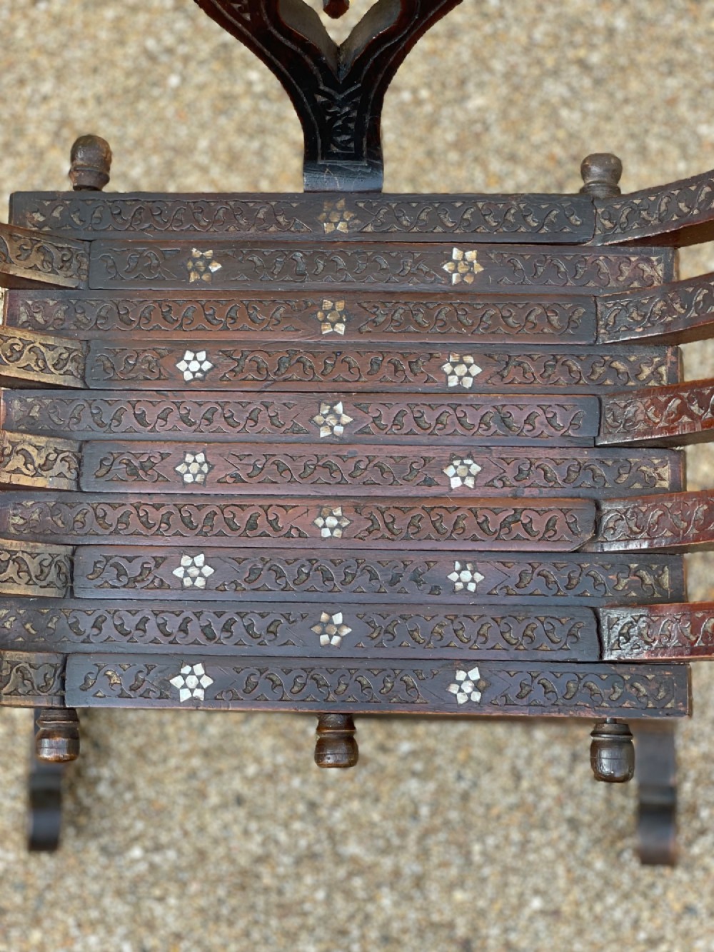 A dark carved wood X-frame armchair featuring intricate Arabic geometric fretwork and inlaid star motifs crafted from iridescent mother of pearl. View V