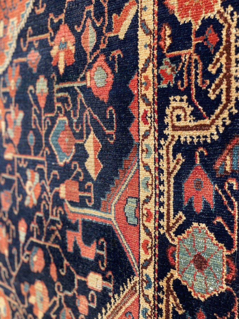 An antique hand-knotted Persian Jozan wool rug featuring a dark navy field filled with floral motifs around a central terracotta red diamond medallion and matching spandrels. View V