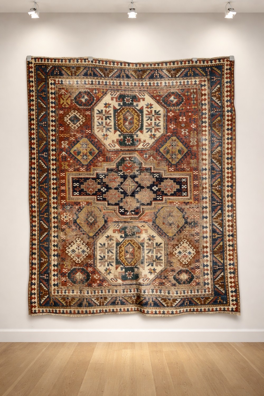 An antique Caucasian Kazak hand-knotted wool rug featuring geometric stepped medallions and latch-hook borders in shades of red, indigo blue, and cream. View IX