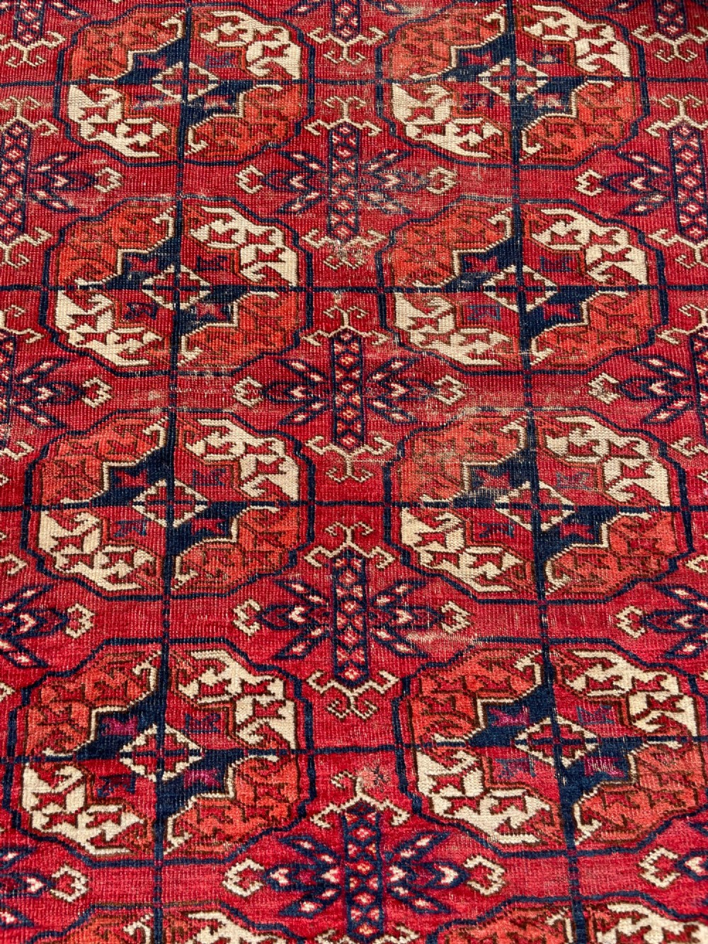 An antique hand-knotted Tekke Turkoman dowry rug featuring repeating octagonal gol motifs in deep red, navy blue, and ivory silk accents. View V