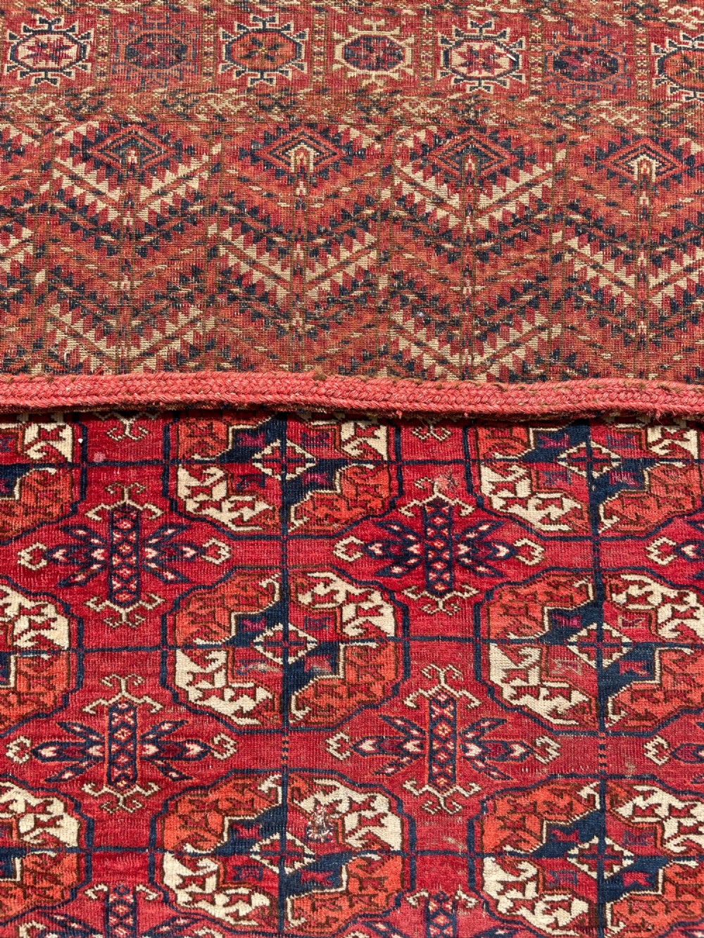 An antique hand-knotted Tekke Turkoman dowry rug featuring repeating octagonal gol motifs in deep red, navy blue, and ivory silk accents. View XI