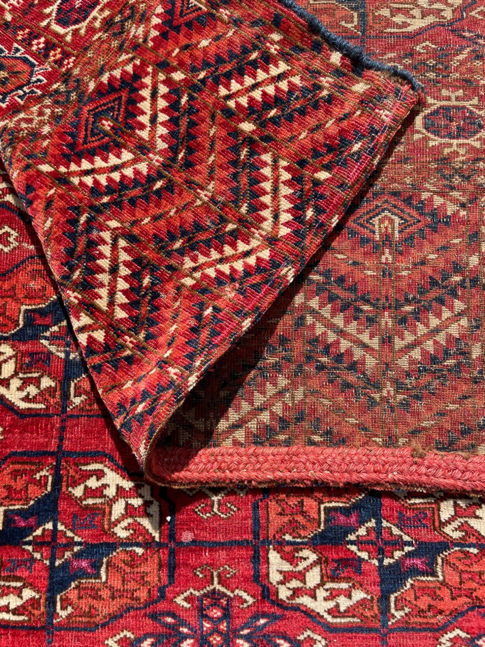 An antique hand-knotted Tekke Turkoman dowry rug featuring repeating octagonal gol motifs in deep red, navy blue, and ivory silk accents. View XII
