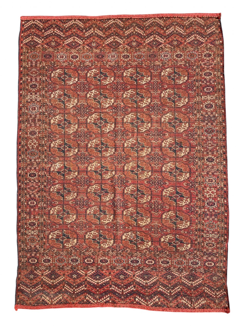 An antique hand-knotted Tekke Turkoman dowry rug featuring repeating octagonal gol motifs in deep red, navy blue, and ivory silk accents. View II
