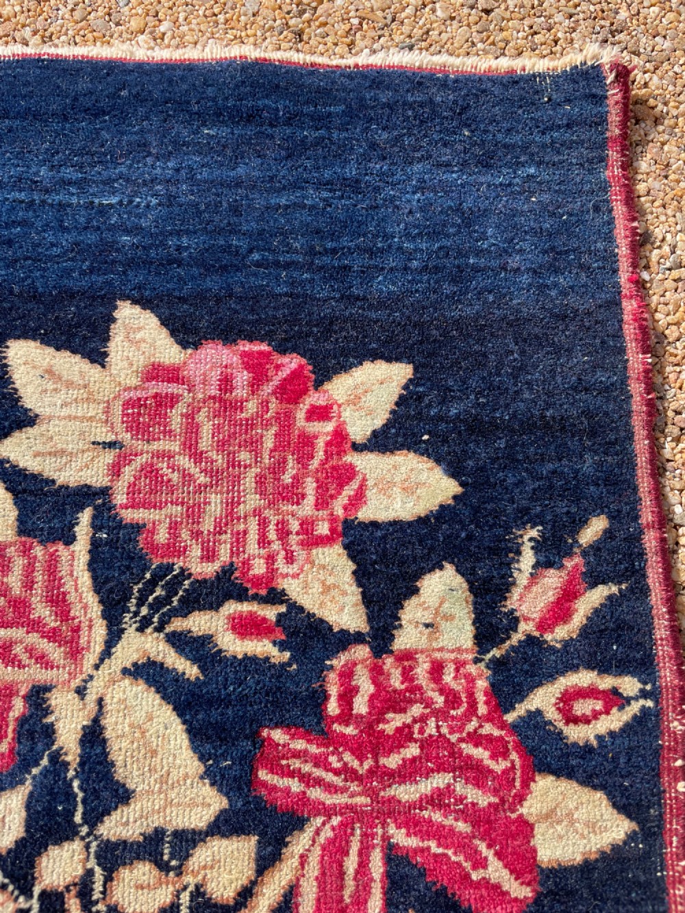 A small antique hand-knotted Kirman rug featuring two birds amongst rose blossoms on a dark navy blue background. View IX
