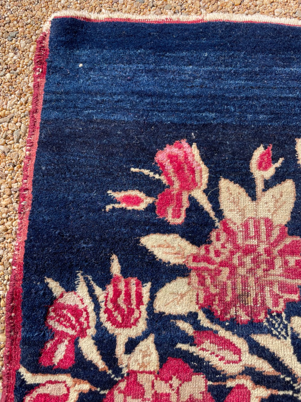 A small antique hand-knotted Kirman rug featuring two birds amongst rose blossoms on a dark navy blue background. View X