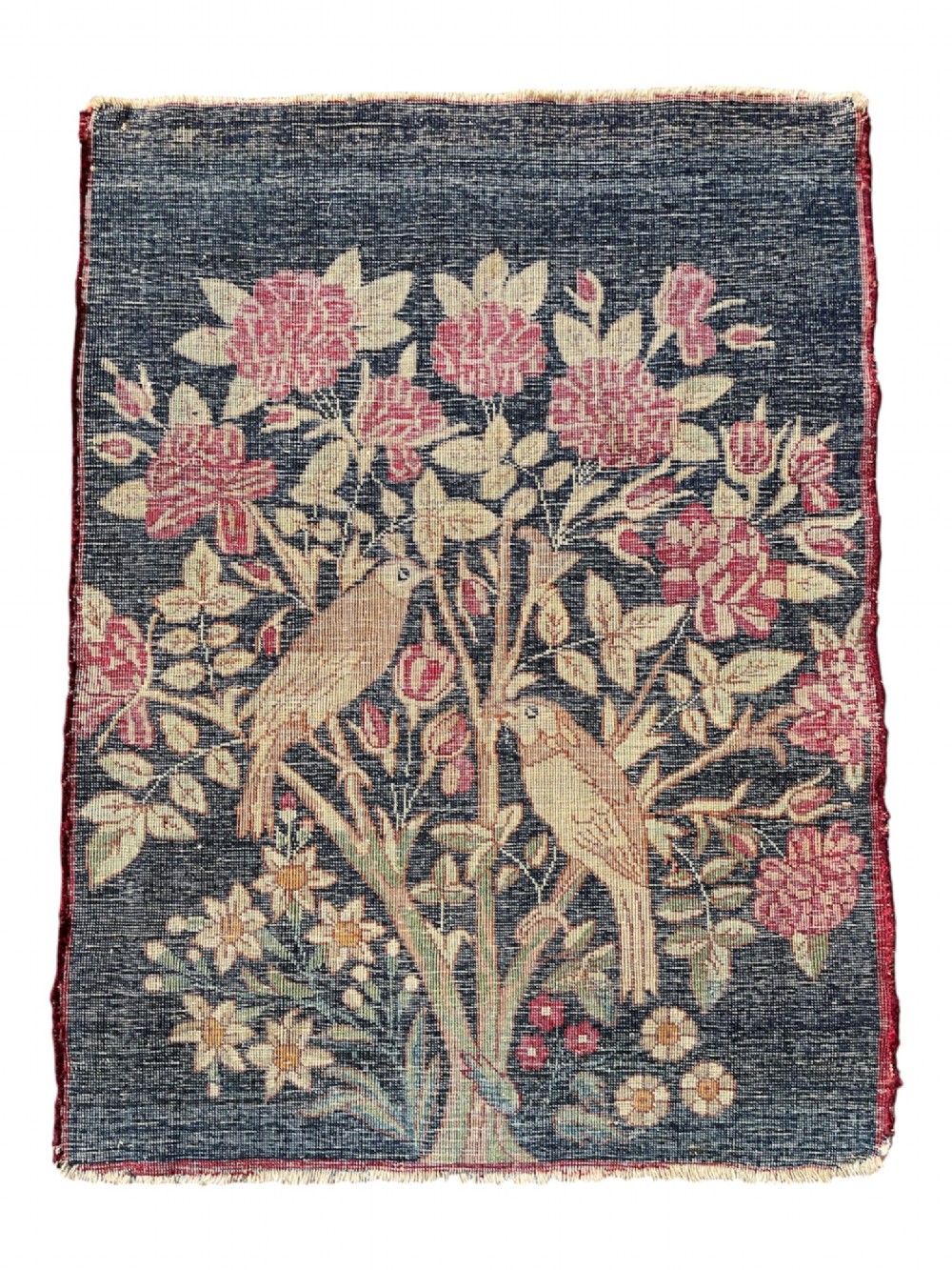 A small antique hand-knotted Kirman rug featuring two birds amongst rose blossoms on a dark navy blue background. View XII