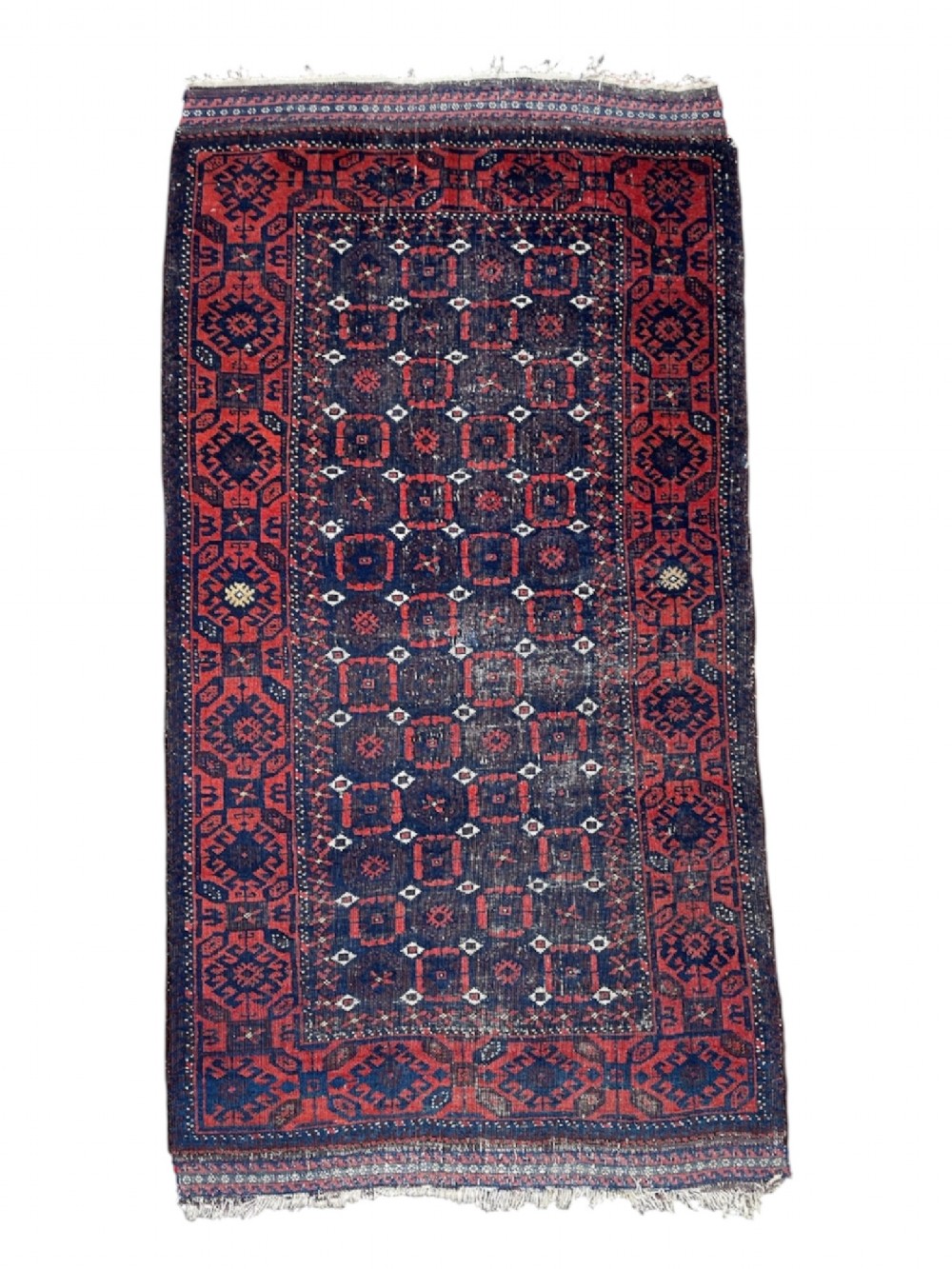 A hand-knotted Baluch rug featuring a navy blue field filled with a repeating geometric Mina Khani pattern framed by deep red borders.