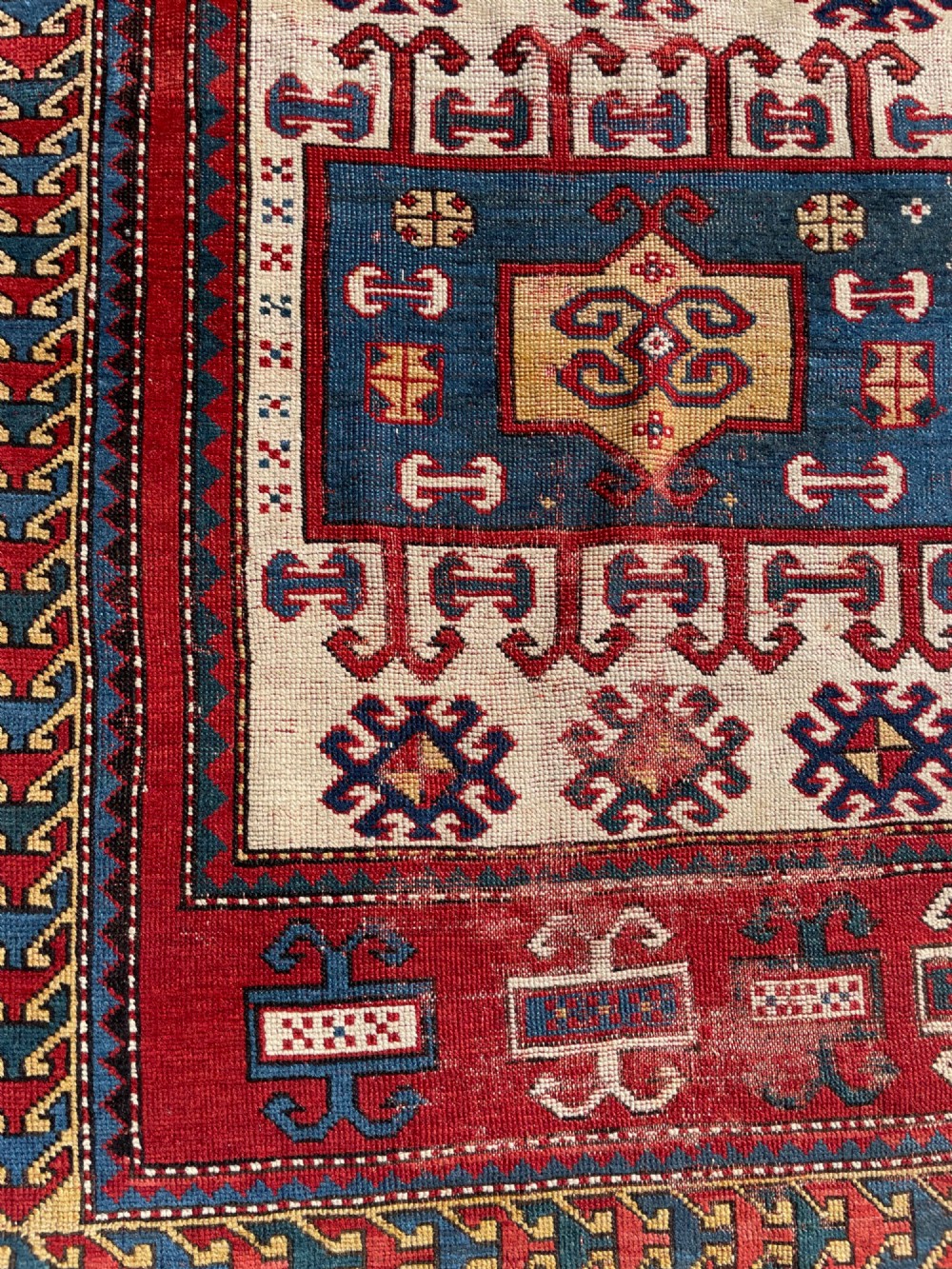 An antique hand-knotted Caucasian Karachov prayer rug featuring a red, ivory, blue, and yellow geometric pattern with a central stepped prayer arch. View IX