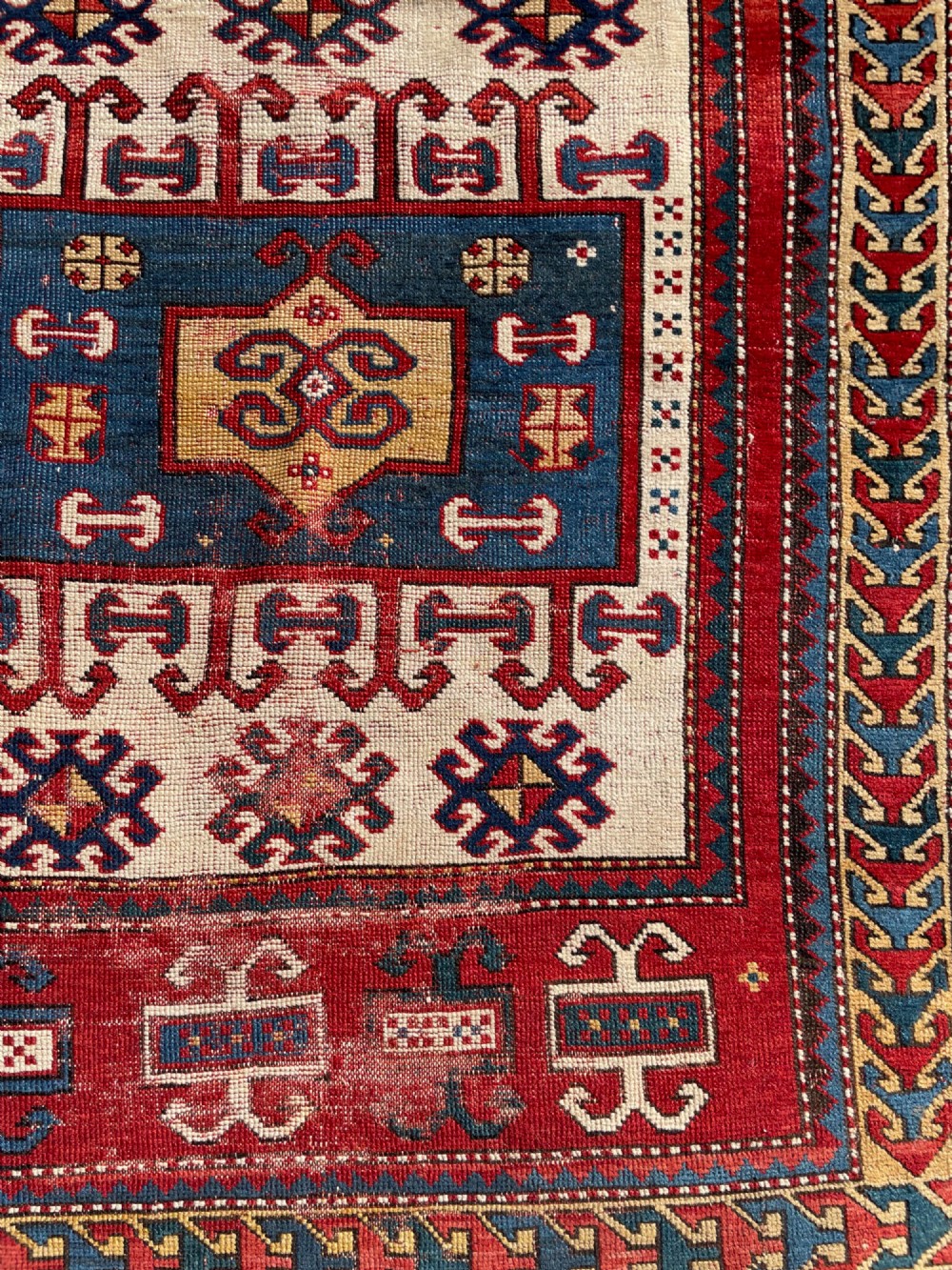 An antique hand-knotted Caucasian Karachov prayer rug featuring a red, ivory, blue, and yellow geometric pattern with a central stepped prayer arch. View X