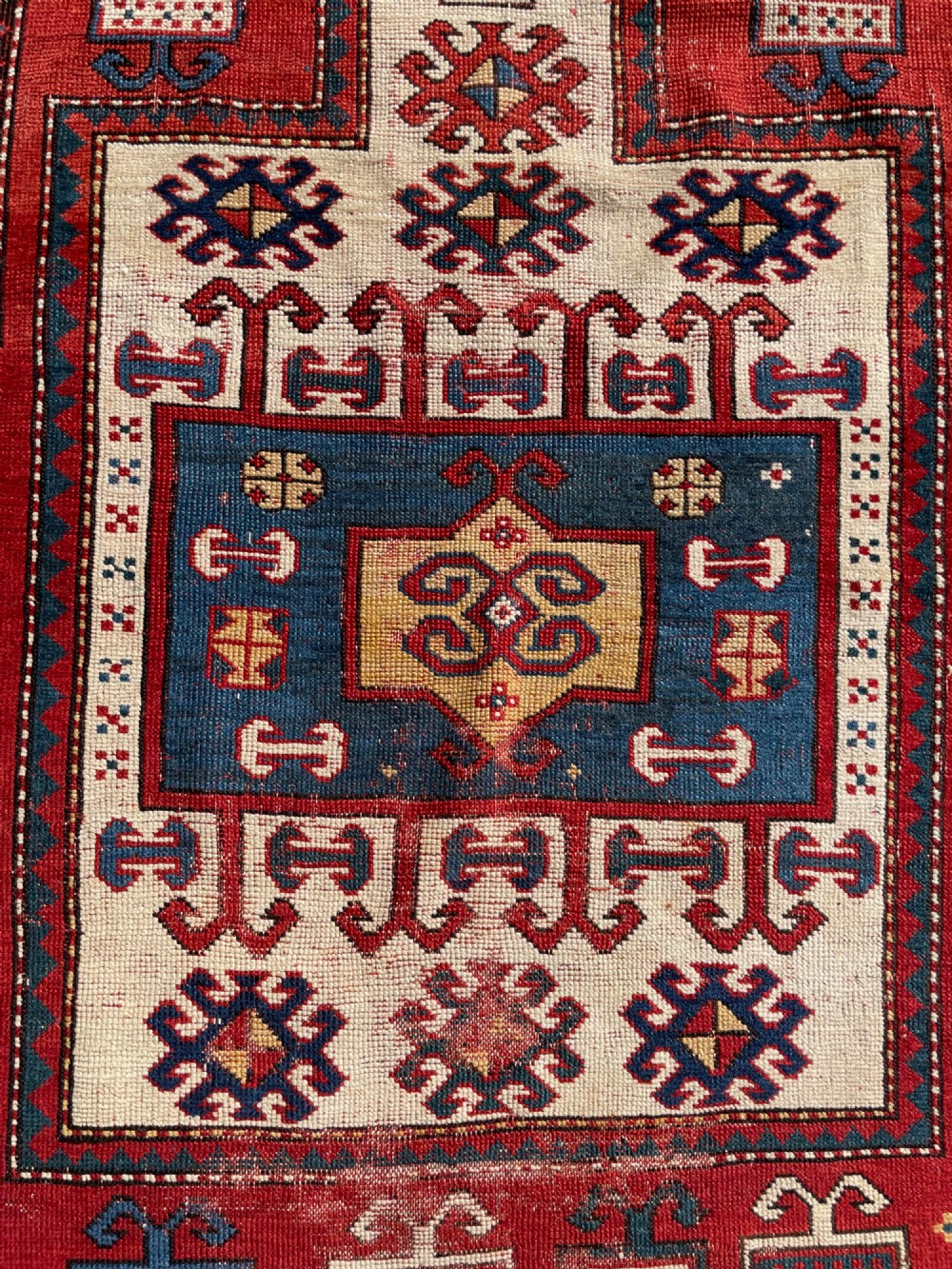 An antique hand-knotted Caucasian Karachov prayer rug featuring a red, ivory, blue, and yellow geometric pattern with a central stepped prayer arch. View XI