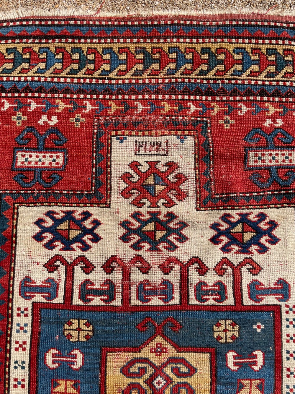 An antique hand-knotted Caucasian Karachov prayer rug featuring a red, ivory, blue, and yellow geometric pattern with a central stepped prayer arch. View XII