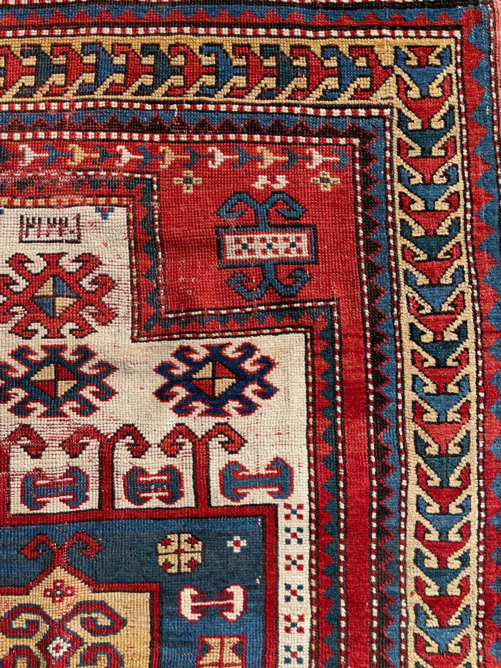 An antique hand-knotted Caucasian Karachov prayer rug featuring a red, ivory, blue, and yellow geometric pattern with a central stepped prayer arch. View XIV