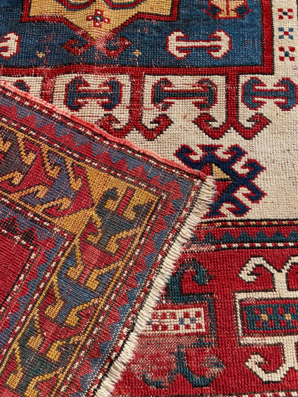 An antique hand-knotted Caucasian Karachov prayer rug featuring a red, ivory, blue, and yellow geometric pattern with a central stepped prayer arch. View XV