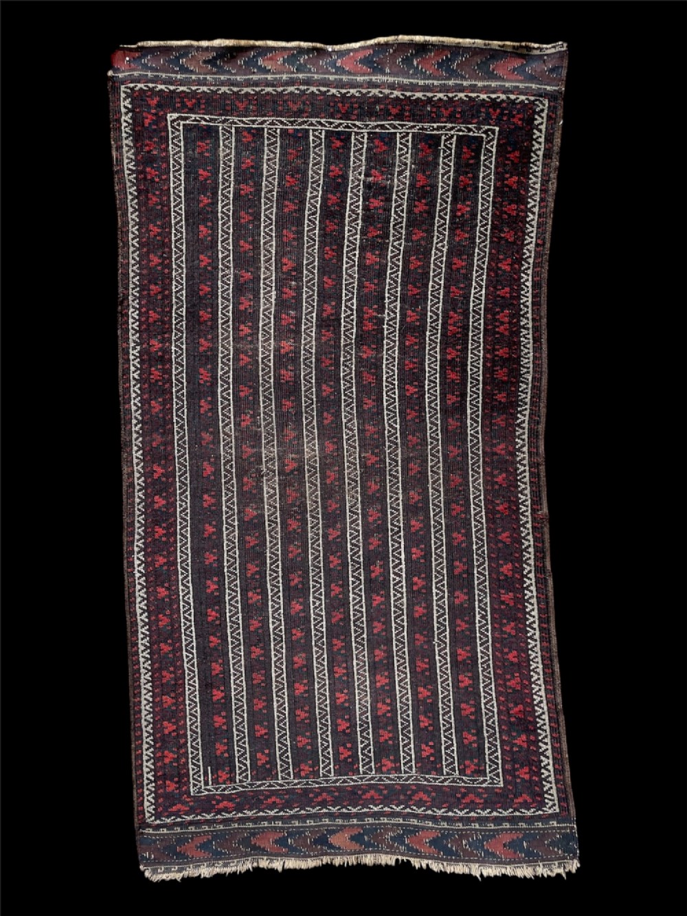 An antique Baluch wool runner rug featuring repeating vertical geometric stripes framed by dark red, navy blue, and ivory patterned borders.