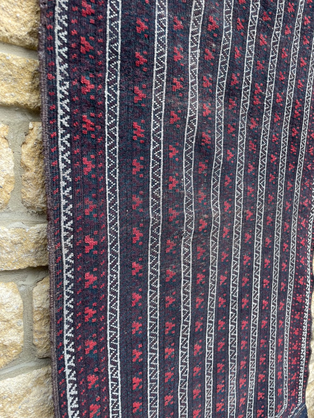 An antique Baluch wool runner rug featuring repeating vertical geometric stripes framed by dark red, navy blue, and ivory patterned borders. View V