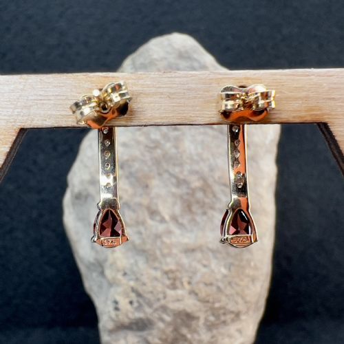 fig 1. A pair of 9ct gold drop earrings featuring curved diamond-set bars terminating in pear-shaped red garnets, accompanied by gold scroll backs.