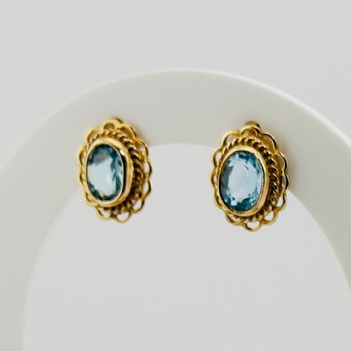 fig 1. A pair of 9ct yellow gold stud earrings featuring oval blue topaz gemstones encased within filigree and rope-twist borders.