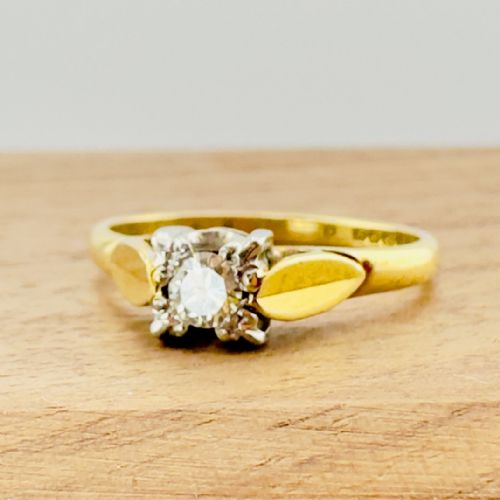 fig 1. A Victorian 18ct yellow gold solitaire ring featuring a central round diamond set in an ornate illusion head with leaf shoulder accents.