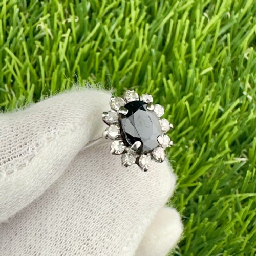 fig 1. An Art Deco cluster ring featuring a central oval dark blue sapphire surrounded by a halo of small diamonds set in 18ct white gold.