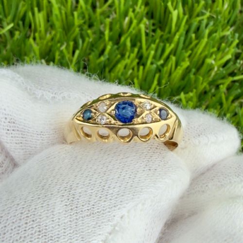 fig 1. An 18ct yellow gold George V boat ring set with three blue sapphires and accent diamonds featuring an openwork carved gallery.
