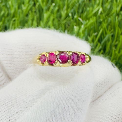fig 1. An 18ct yellow gold ring featuring five graduated cushion-cut rubies set across a carved setting.