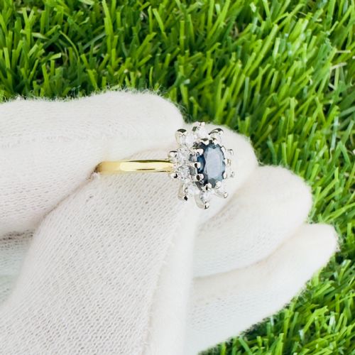 fig 1. An 18ct gold cluster ring featuring a central oval blue sapphire surrounded by a starburst halo of small diamonds.