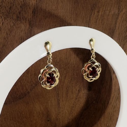 fig 1. A pair of 9ct yellow gold drop stud earrings featuring oval red garnets framed by openwork floral metalwork.