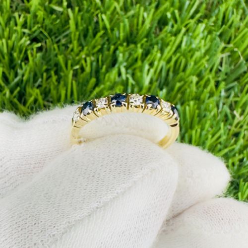 fig 1. An 18ct yellow gold half eternity ring featuring an alternating row of four round blue sapphires and four round diamonds held in claw settings.