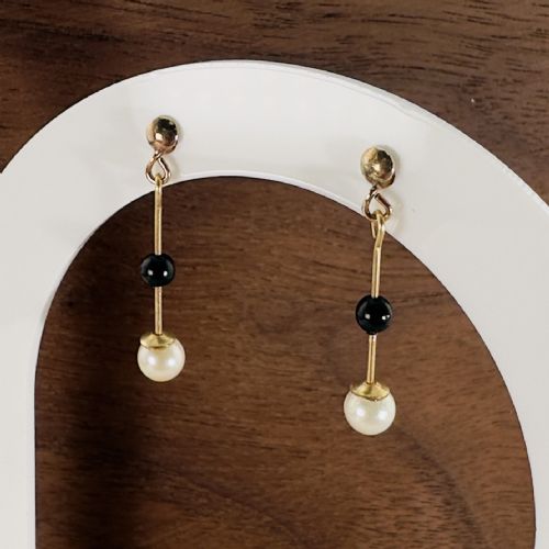 fig 1. A pair of 9ct yellow gold drop earrings featuring ball studs, vertical wire links holding central black onyx beads, and cream pearl drops.