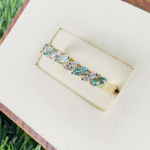 fig 1. An 18ct yellow gold band featuring a row of diagonal baguette cut emeralds interspersed with small round brilliant diamonds.