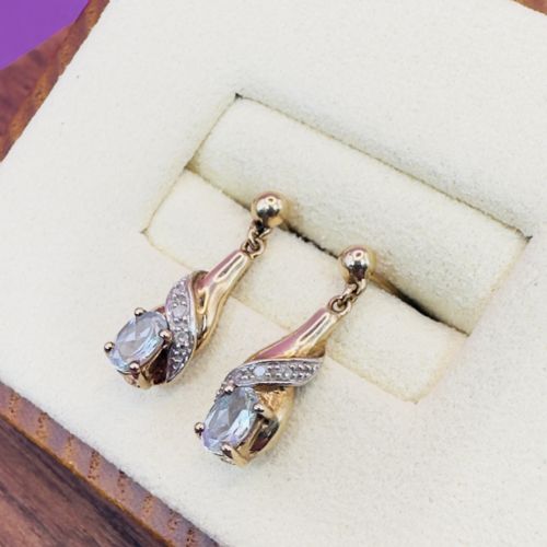 fig 1. Pair of 9ct yellow gold drop stud earrings featuring oval-cut light blue aquamarines enclosed in diamond-paved swirl mounts.