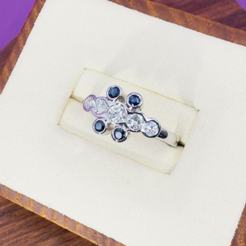 fig 1. A platinum ring featuring a central row of five diamonds flanked by dark blue sapphires in rub-over bezel settings.