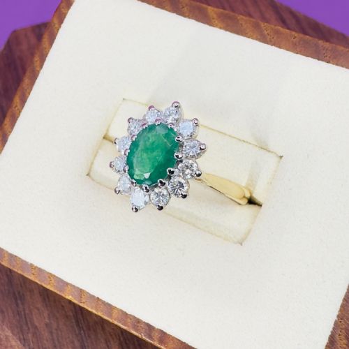 fig 1. An 18ct yellow gold ring set with an oval faceted central green emerald and a halo cluster of round brilliant diamonds.