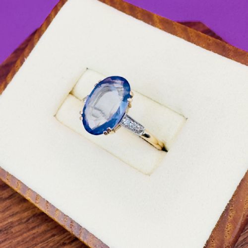fig 1. An Art Deco ring featuring a large oval cut blue sapphire in claw settings with diamond shoulders on a gold band.