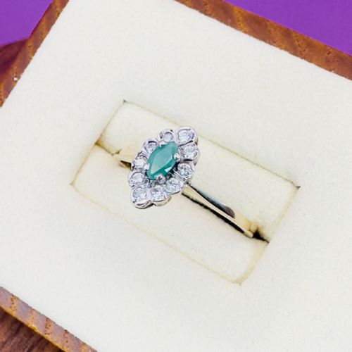 fig 1. A 9ct yellow gold ring set with a central marquise-cut green emerald surrounded by a cluster halo of round diamonds.