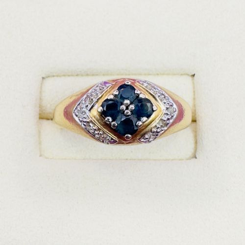 fig 1. An 18ct yellow gold ring featuring a central diamond-shaped panel set with four round blue sapphires, flanked by diamond-set shoulders.