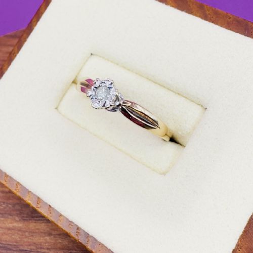 fig 1. A 9ct yellow gold ring featuring a central round diamond set within a starburst illusion mount with carved shoulders.