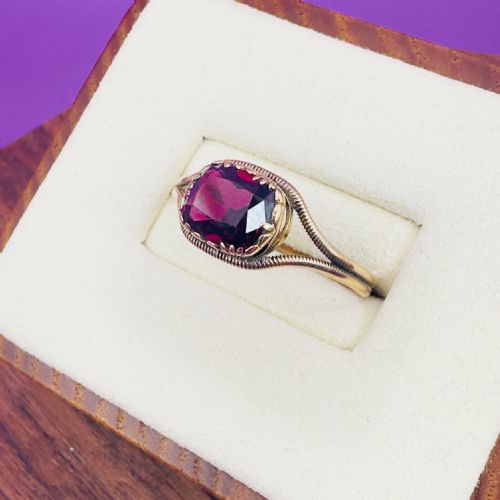 fig 1. A Georgian gold solitaire ring featuring a cushion-shaped deep red garnet set within split reeded shoulders.