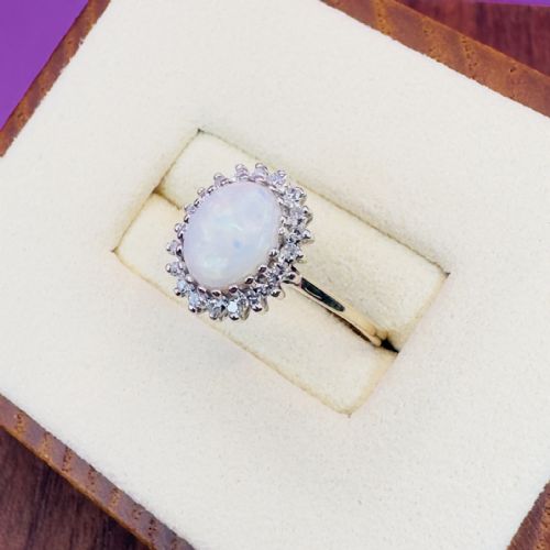fig 1. An oval cabochon opal framed by a halo of diamonds on a slim yellow gold band.