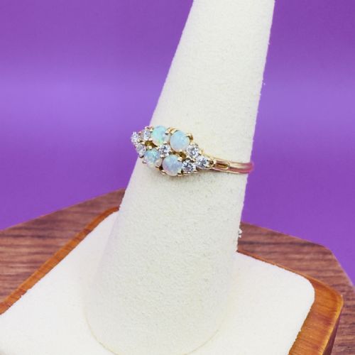 fig 1. An 18ct yellow gold ring set with four round cabochon opals flanked by small round diamonds in a cluster design.