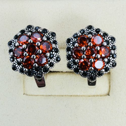 fig 1. A pair of sterling silver hinge back cluster earrings featuring round faceted orange mandarin garnets encircled by small black tourmaline stones.
