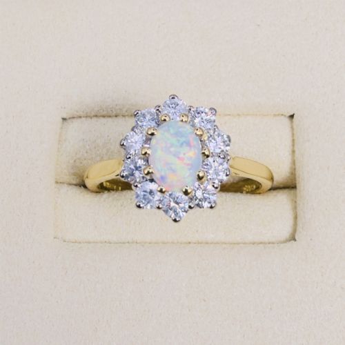 fig 1. An 18ct yellow gold ring featuring an oval cabochon opal surrounded by a halo of brilliant-cut diamonds.
