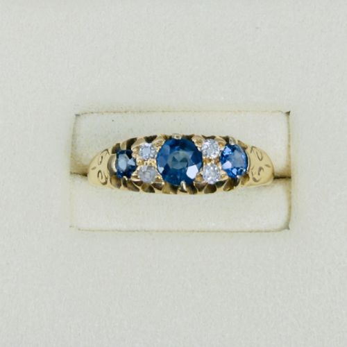 fig 1. An 18ct yellow gold Edwardian ring set with three oval blue sapphires and four diamond accents featuring carved scroll shoulders.