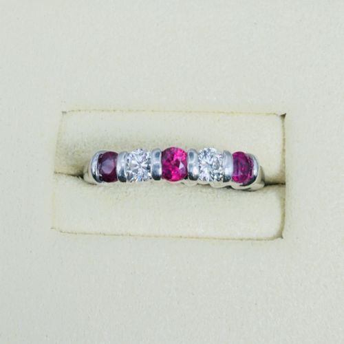 fig 1. An 18ct white gold band ring featuring three round red rubies alternating with two round diamonds in a bar setting.