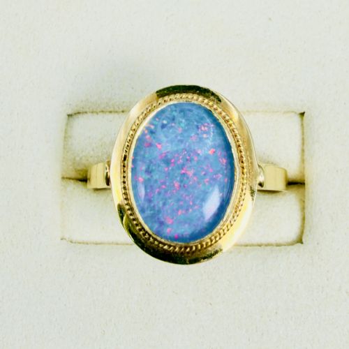 fig 1. An oval blue boulder opal cabochon gemstone set in a 14ct yellow gold ring with a rope twist bezel border.
